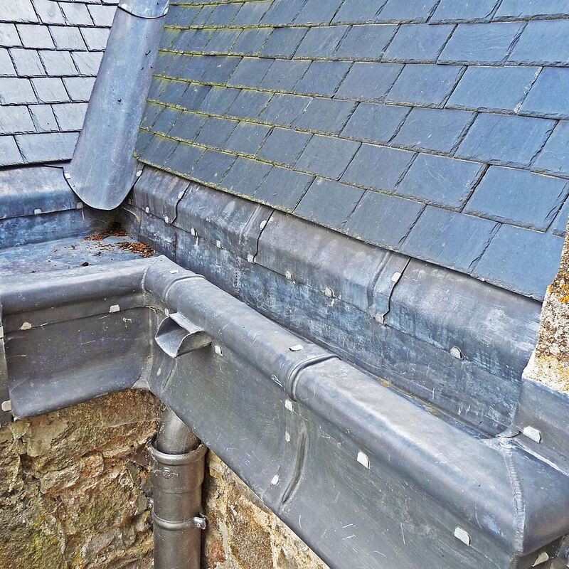 Gouttière en zinc au bord d'une toiture en ardoise
